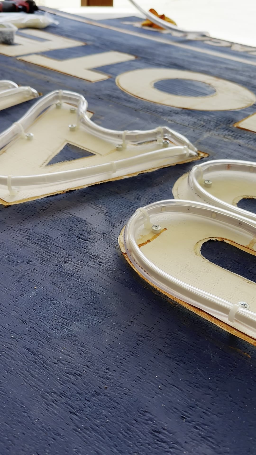 LED strip inside clear vinyl tubing fastened around a carved wooden letter