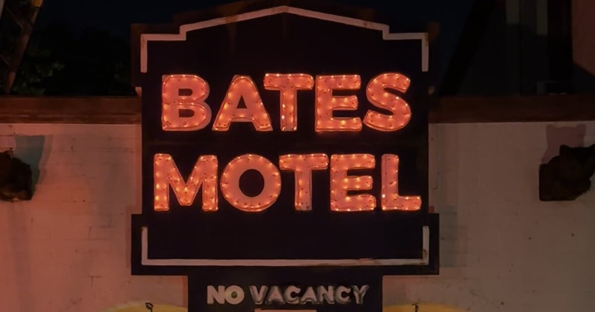 DIY Bates Motel sign lit up in orange faux neon on a house for Halloween