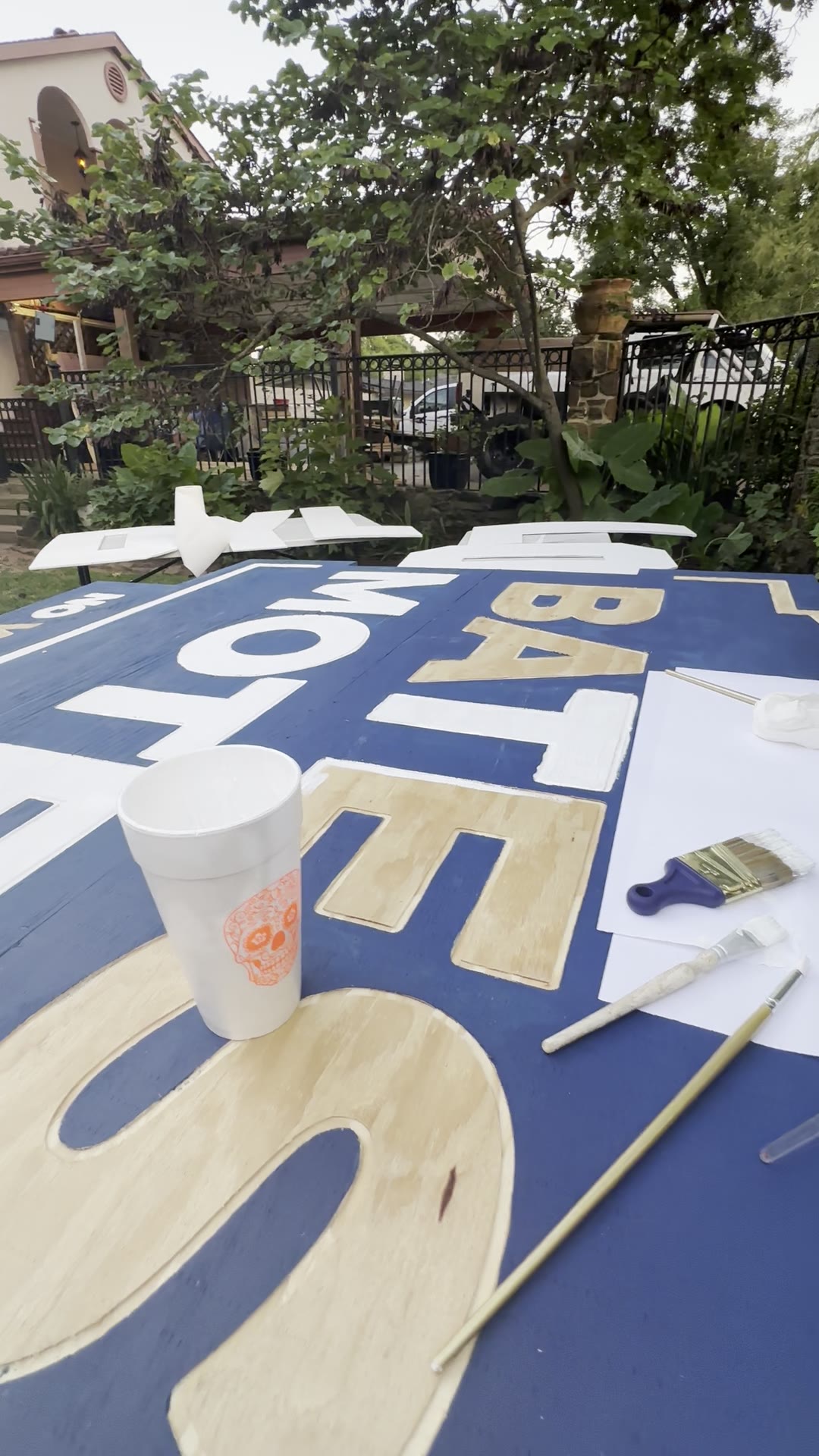 Painting white letters on the blue Bates Motel sign, with some carved letters still bare plywood